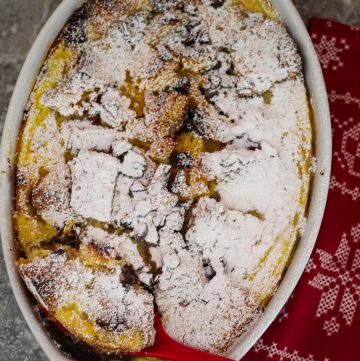 A baking dish with a baked pudding dusted with confectioners sugar.