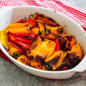 A white baking dish with roasted mini red peppers.