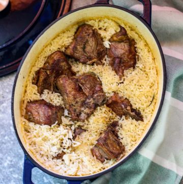 A blue, oval Dutch Oven showcasing a baked casserole with lamb and rice.