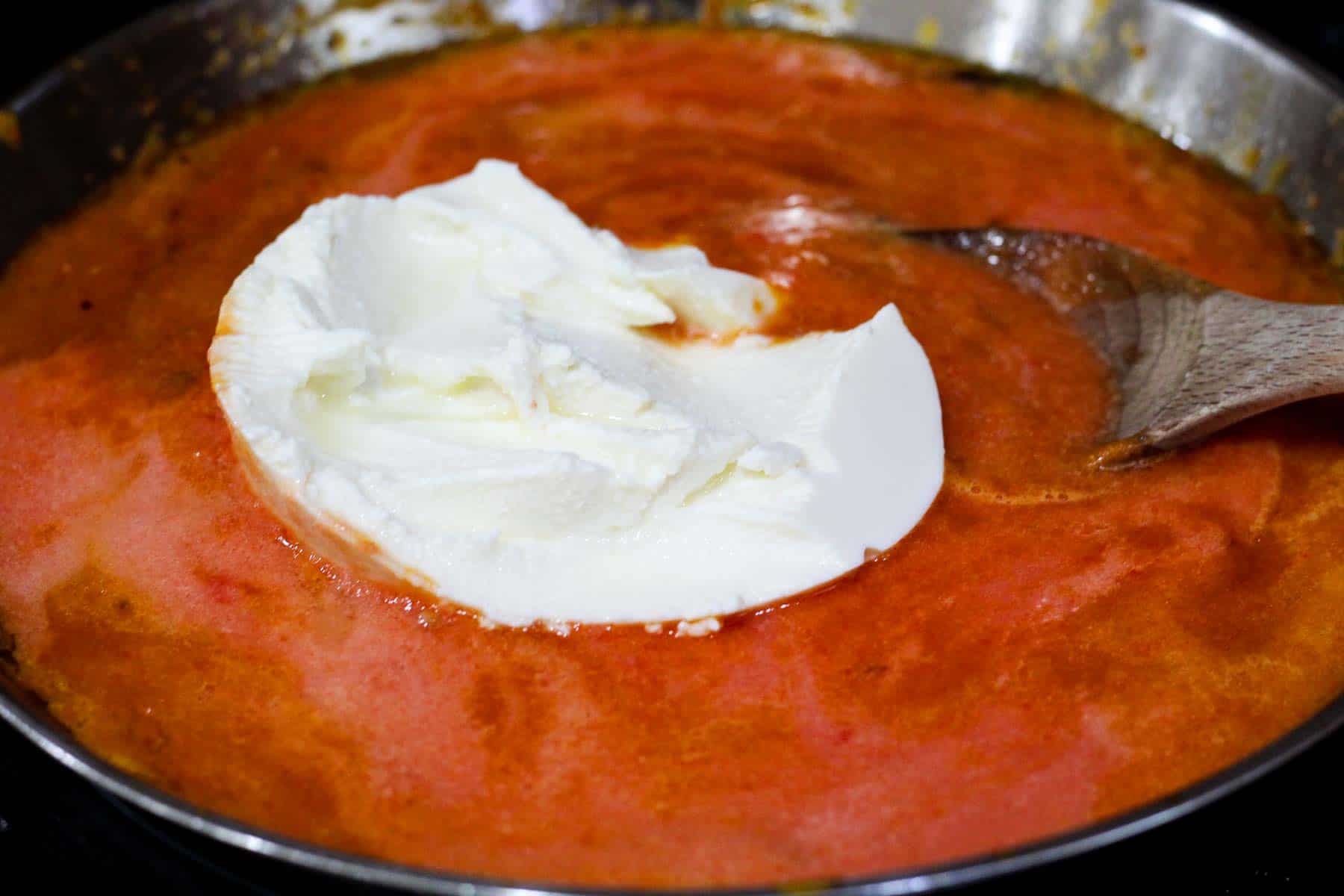 Pepper sauce cooking and ricotta is added in but not mixed with the sauce yet.