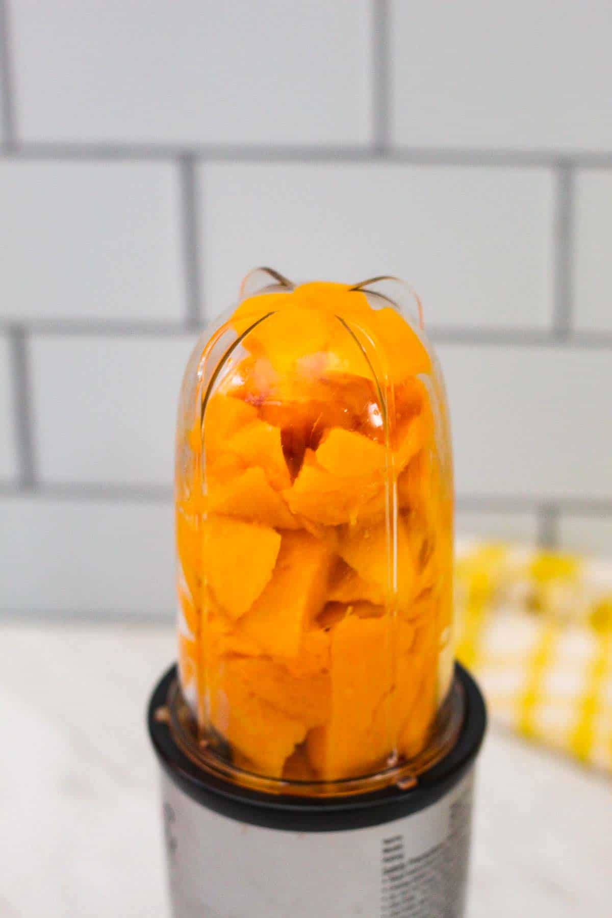 A blender with chunks of fresh mango.