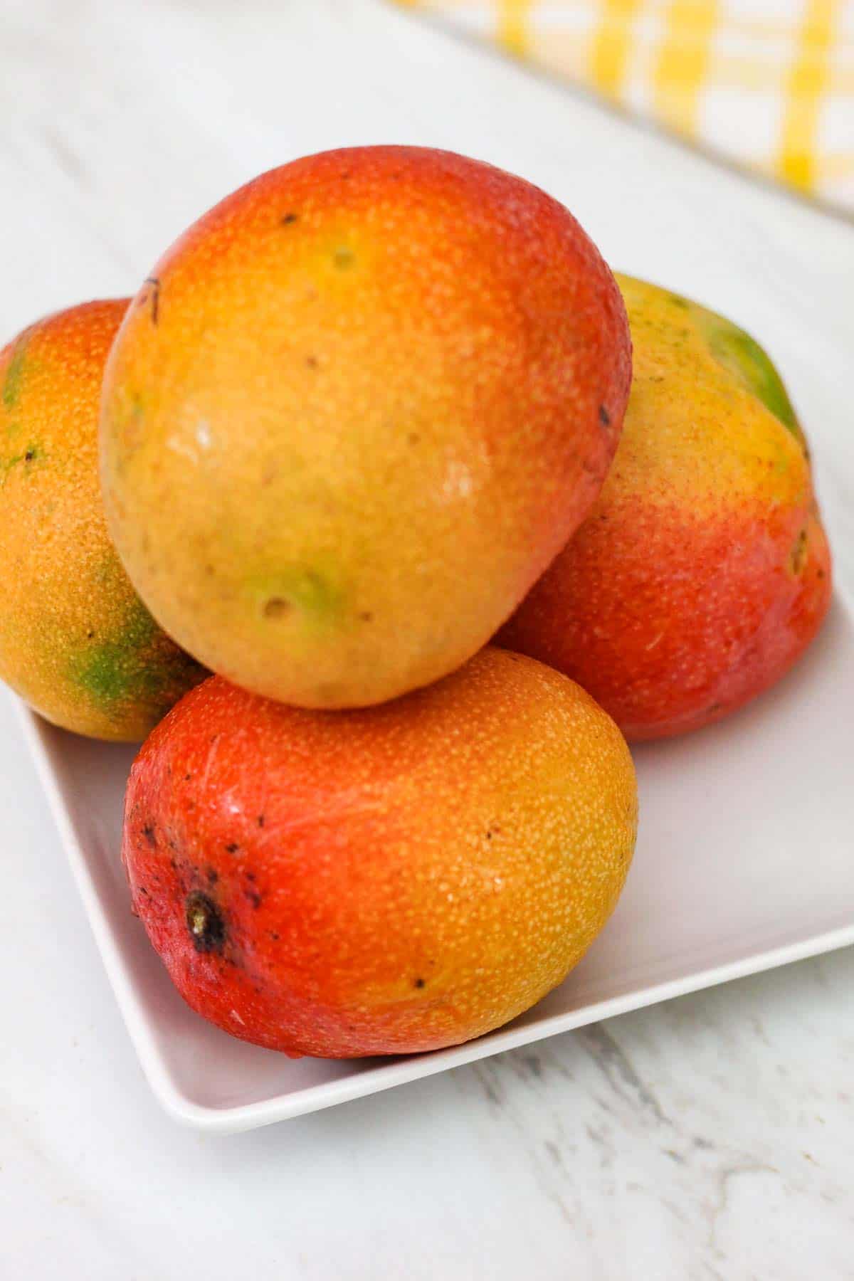 Fresh mangoes from our mango tree on a plate over a white counter. 