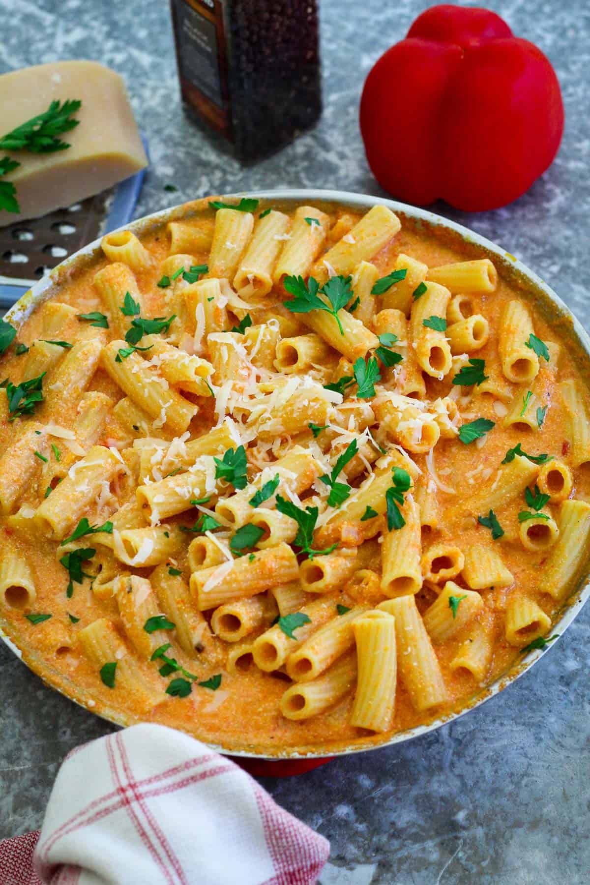 Skillet with rigatoni in an orange, creamy sauce. There's parsley and cheese over the pasta, ready for serving.