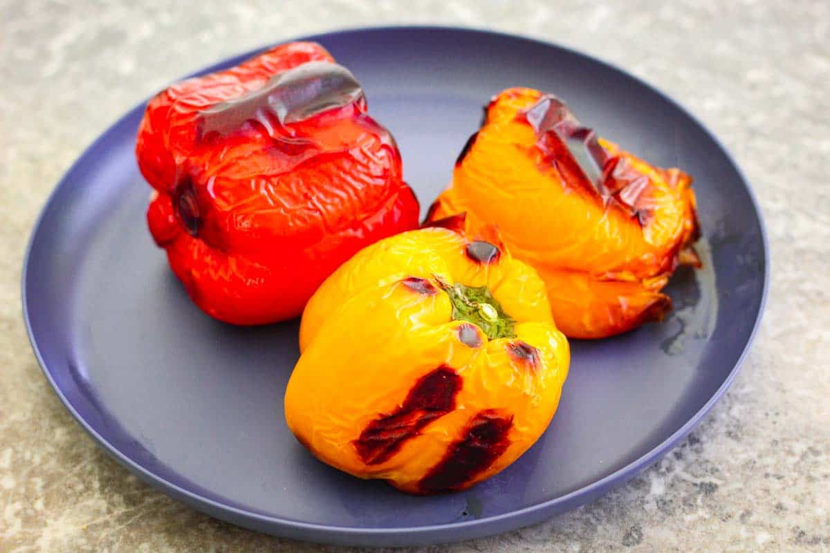 Roasted bell peppers on a platter, they look slightly charred.
