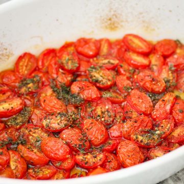 Roasted small tomatoes shown still in a baking tray.