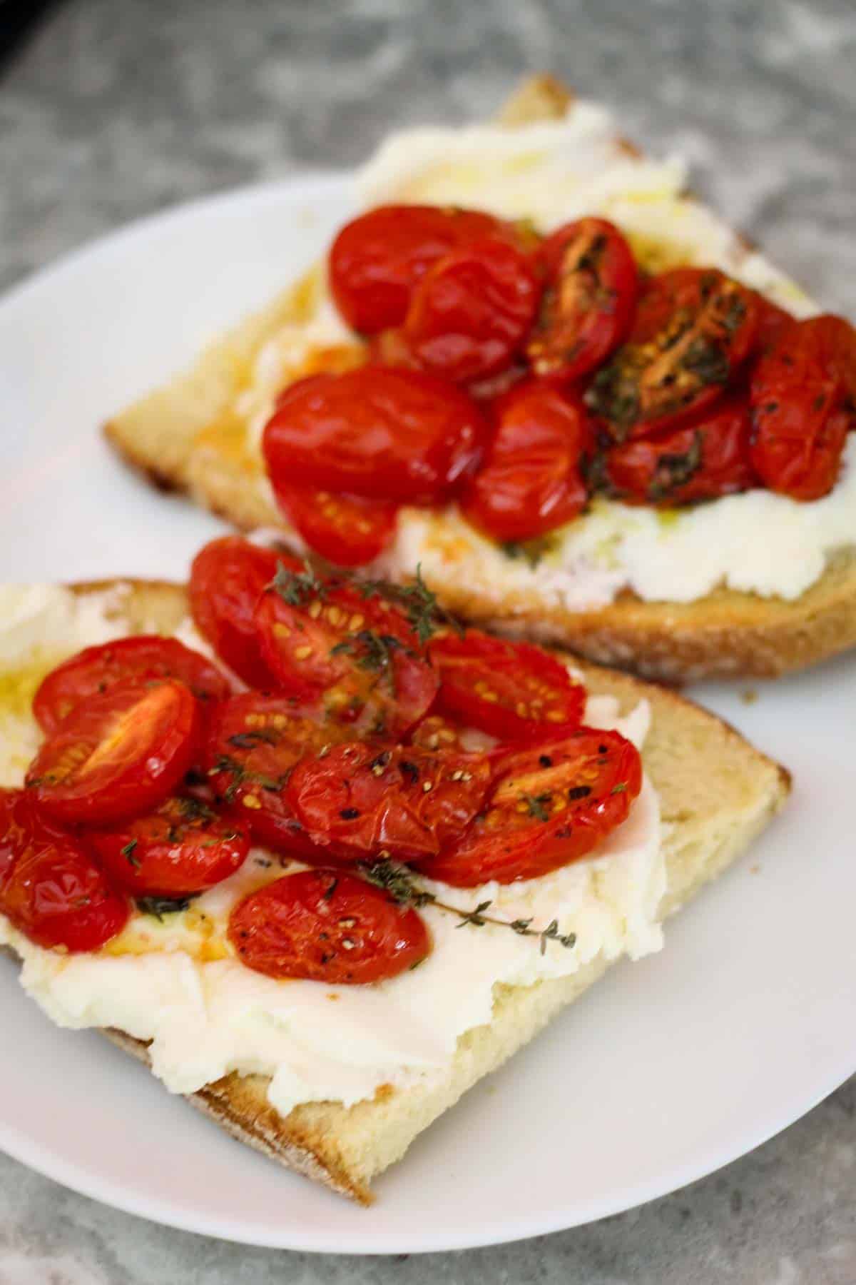 Ricotta toast with roasted tomatoes on a plate.