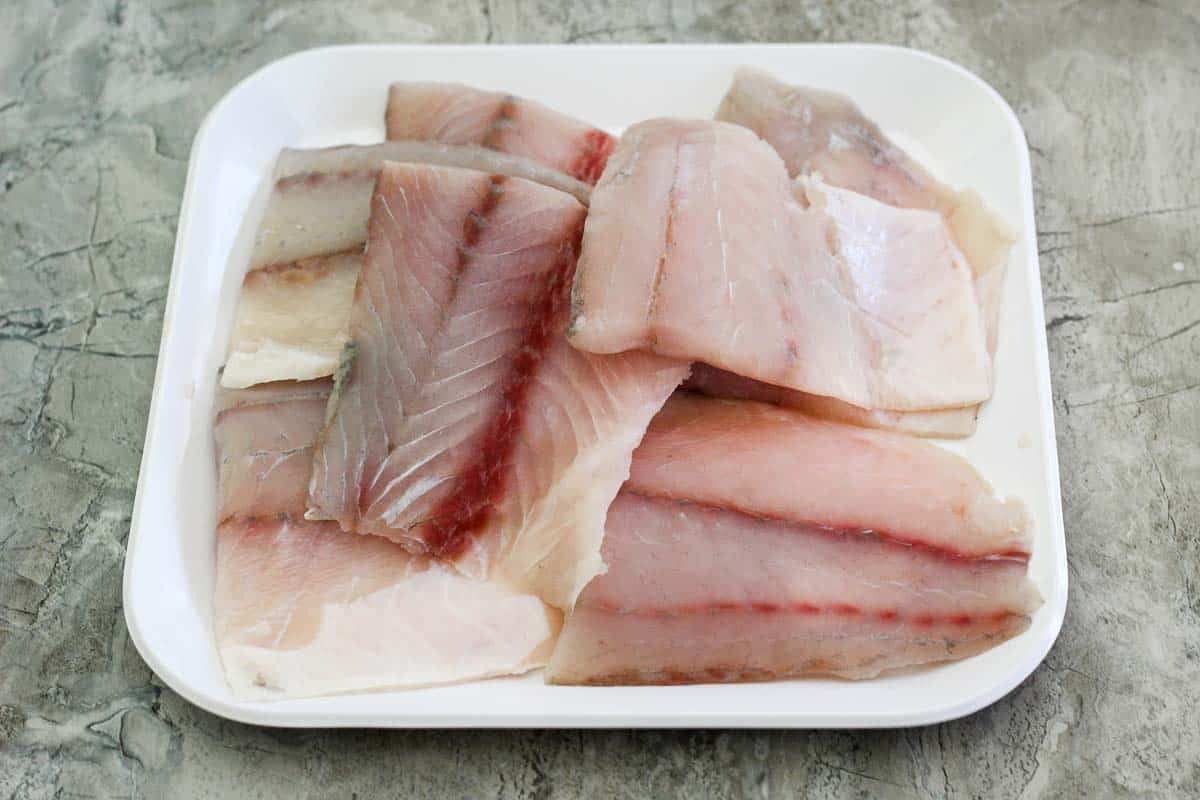 Barramundi fish fillets on a square platter, uncooked. 