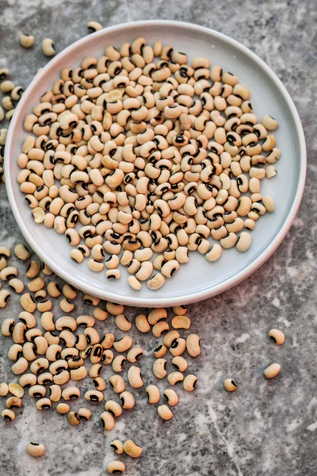 Dry black eyed peas on a plate and on the counter. 