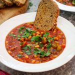 A plate with black eyed peas soup, served with bread and garnished bread.