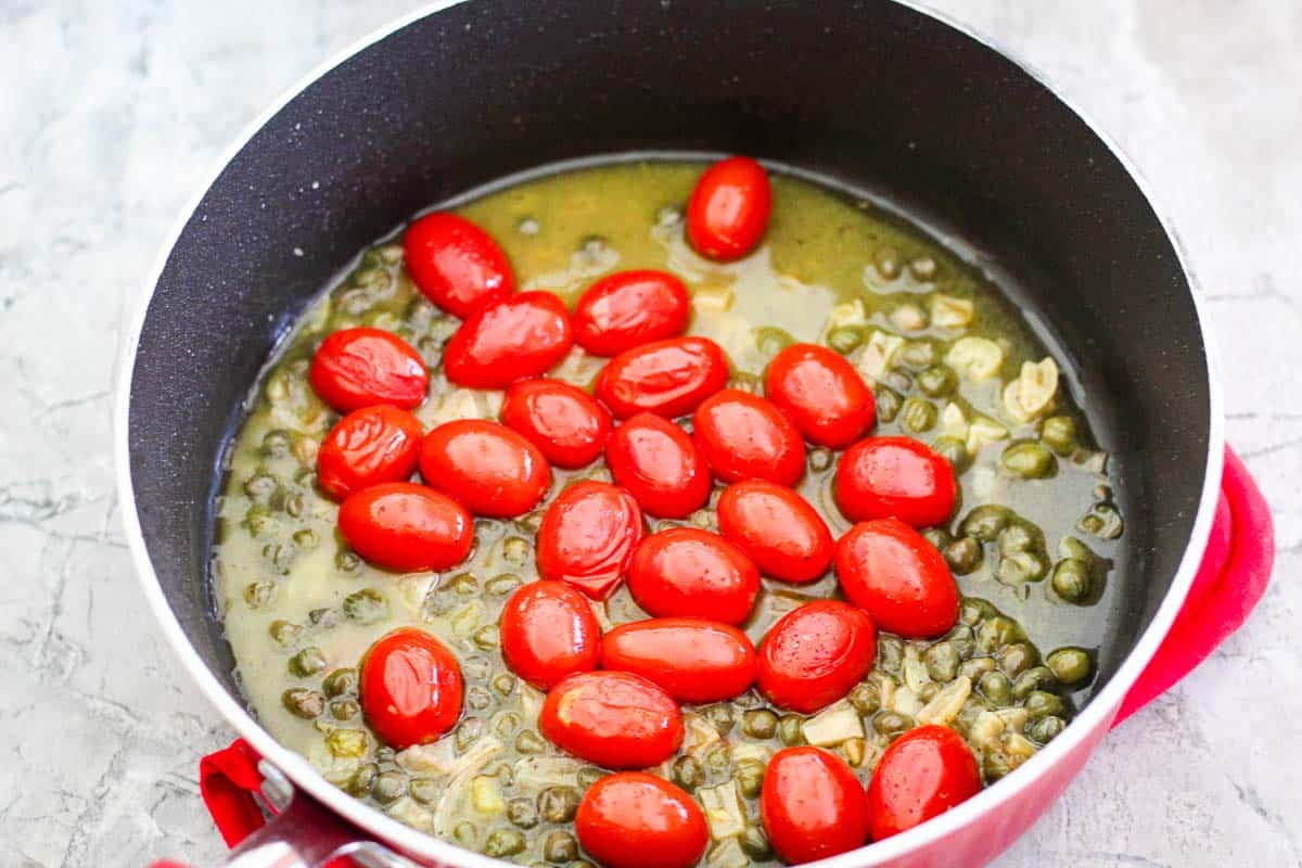 A dish sauce pan with grape tomatoes, capers and lemon sauce. 