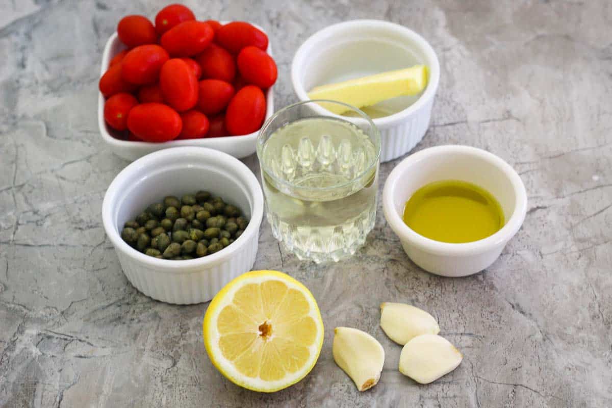 Ingredients for capers lemon sauce: grape tomatoes, butter, capers, white wine, capers, lemon, garlic and olive oil. 