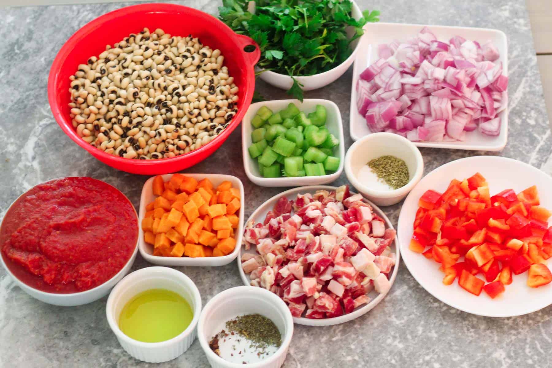 Ingredients for cooking the Black Eyed peas soup: black eyed peas, parsley, onion, celery, carrots, red bell pepper, pancetta, crushed tomatoes, olive oil, and lots of herbs.