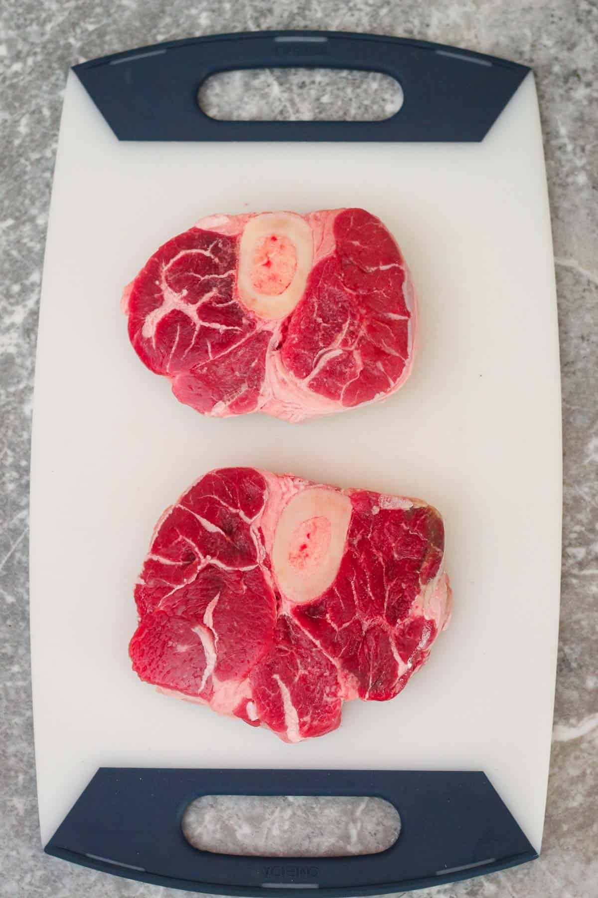 Raw beef shanks (2) in a cutting board.
