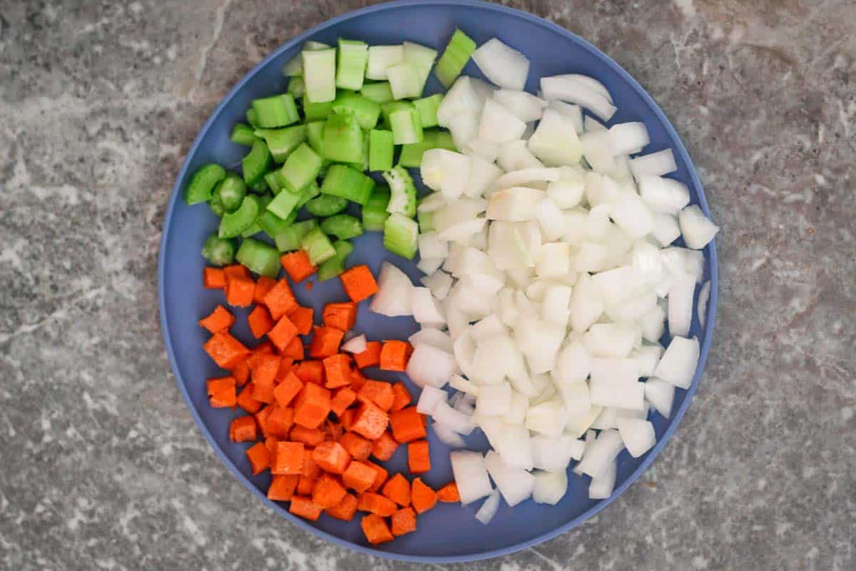 Chopped veggies on a platter, you can see carrots, celery and onions.