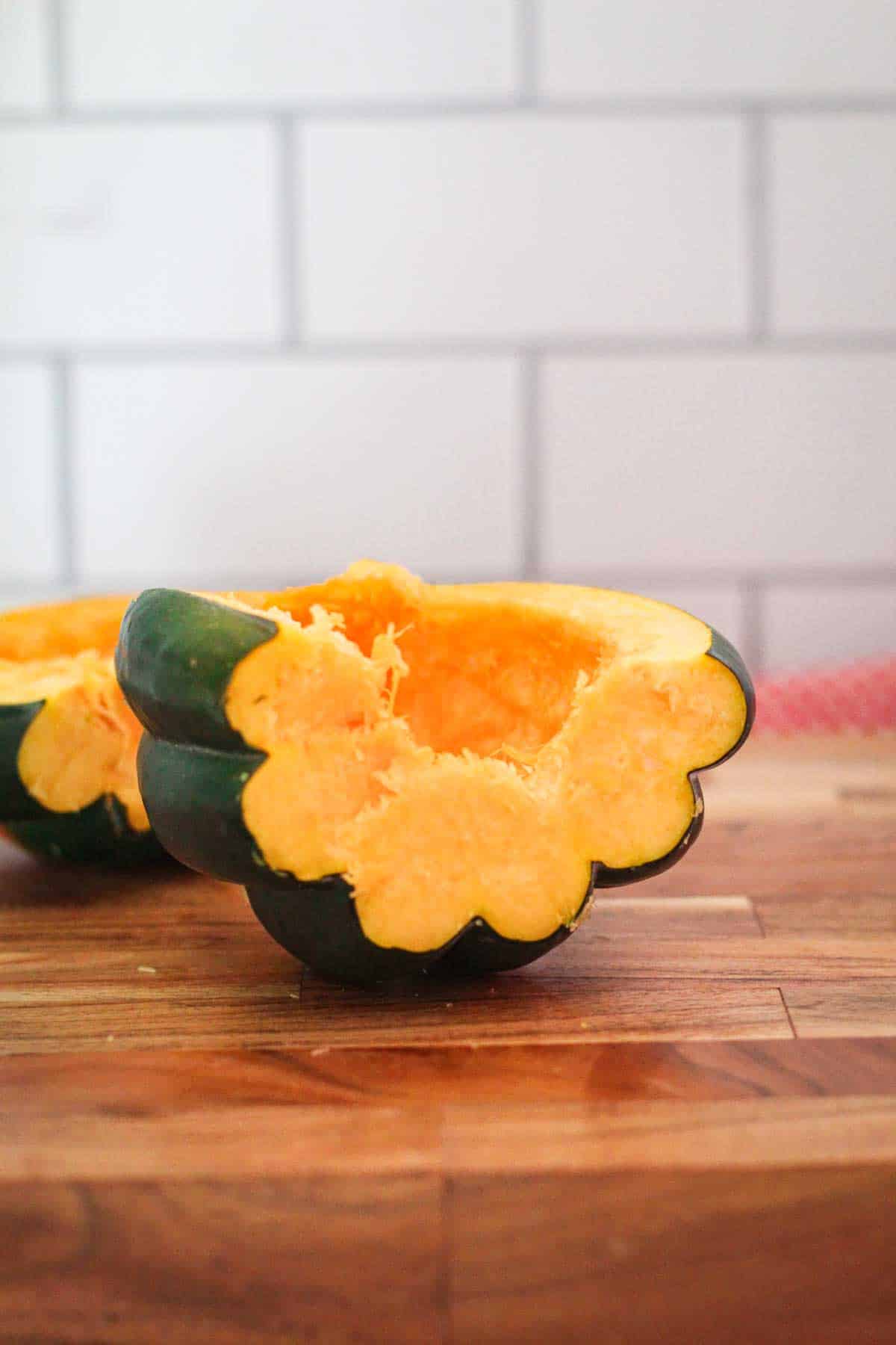 A cutting board showing halved and deseeded acorn squash. 