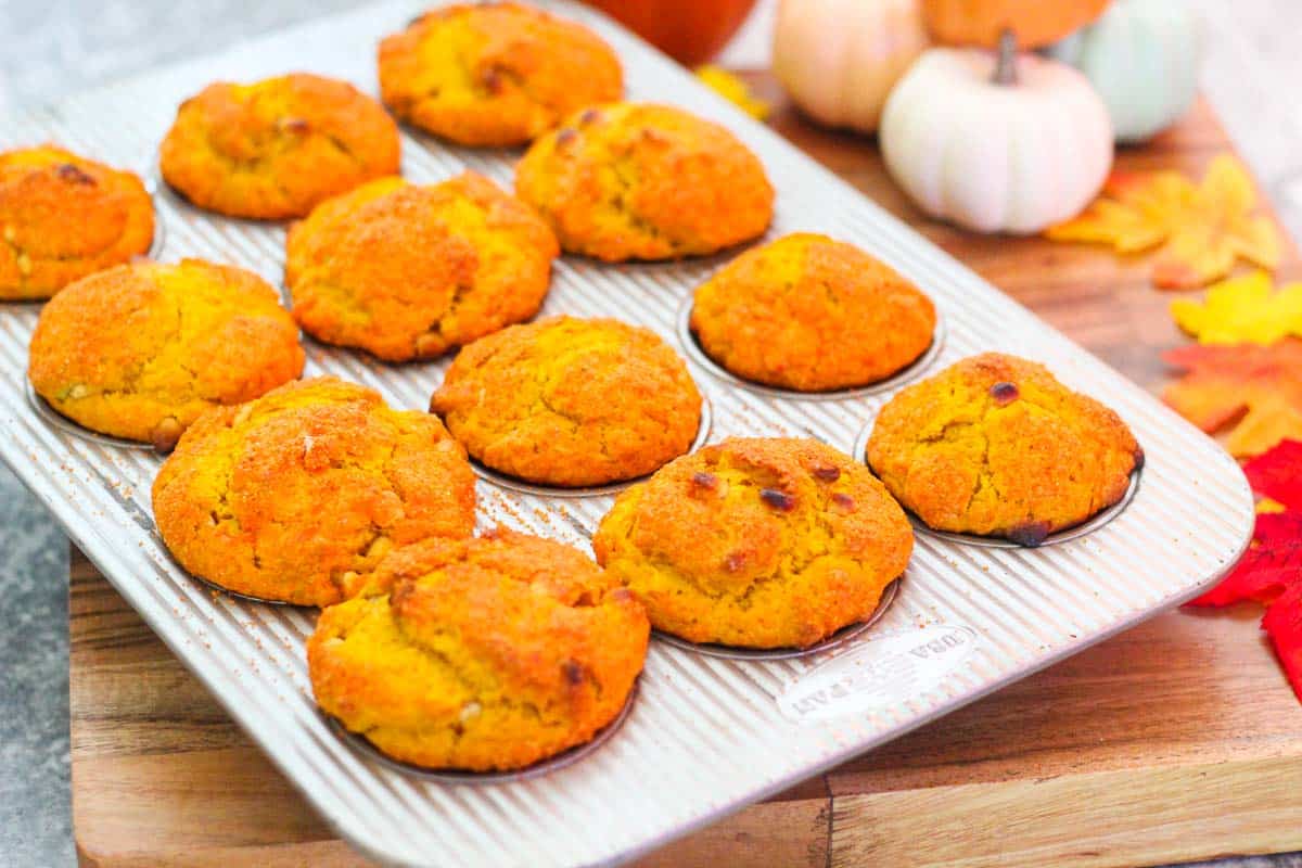Baked Pumpkin Muffins on the baking tray surrounded by Fall colors and decorations. 