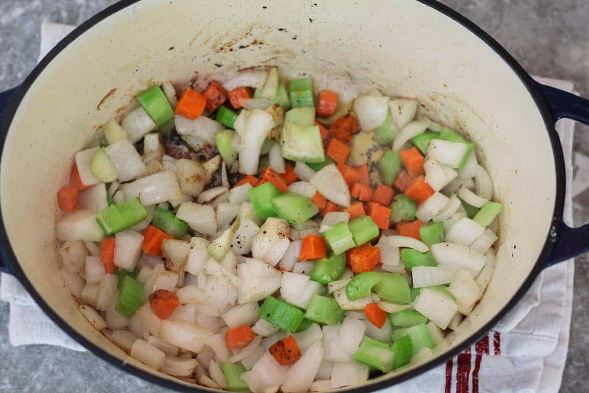 Sauteing veggies in the dutch oven, onions, carrots and celery are all mixed together.