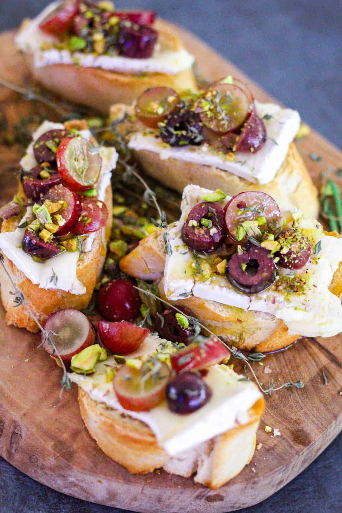 Crostinis with brie, grapes and pistachios drizzled with honey & garnished with thyme and rosemary.