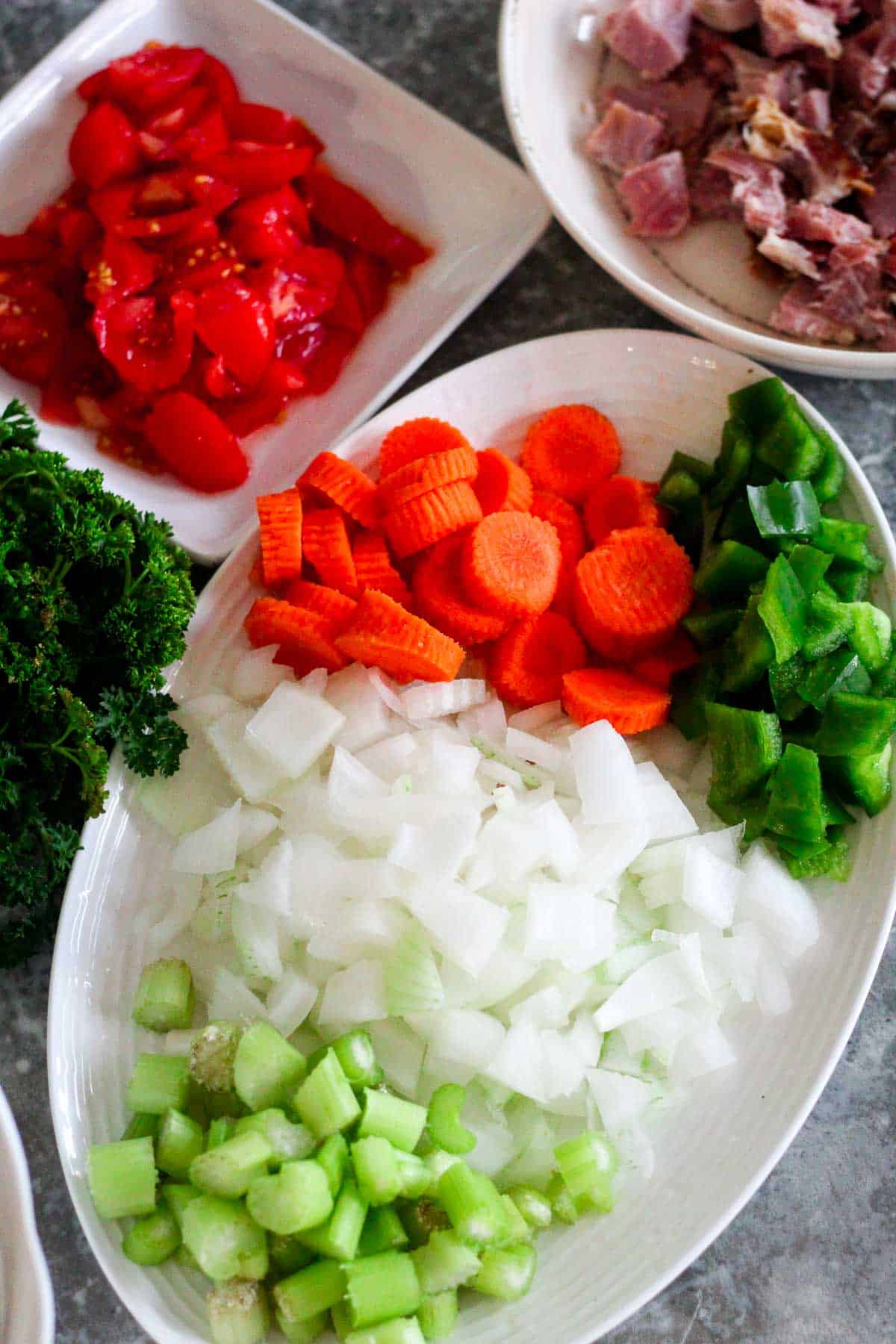 Chopped vegetables for soup: celery, onions, green pepper, carrot, diced tomatoes and parsley are visible.