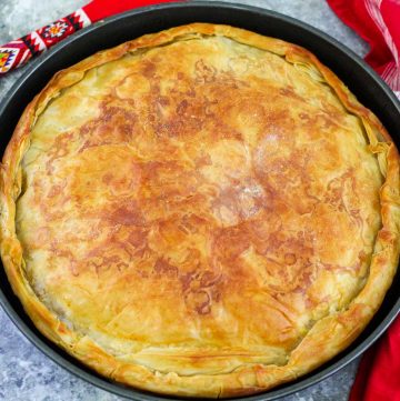 A phyllo pie, just baked, shown in a round baking tray.