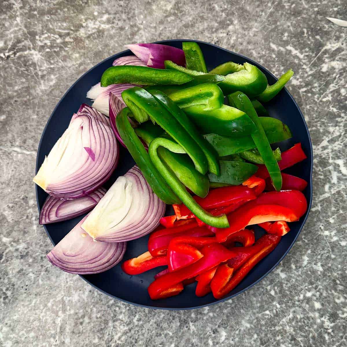 Chopped Veggies on a platter: green bell peppers, red bell peppers, red onion.