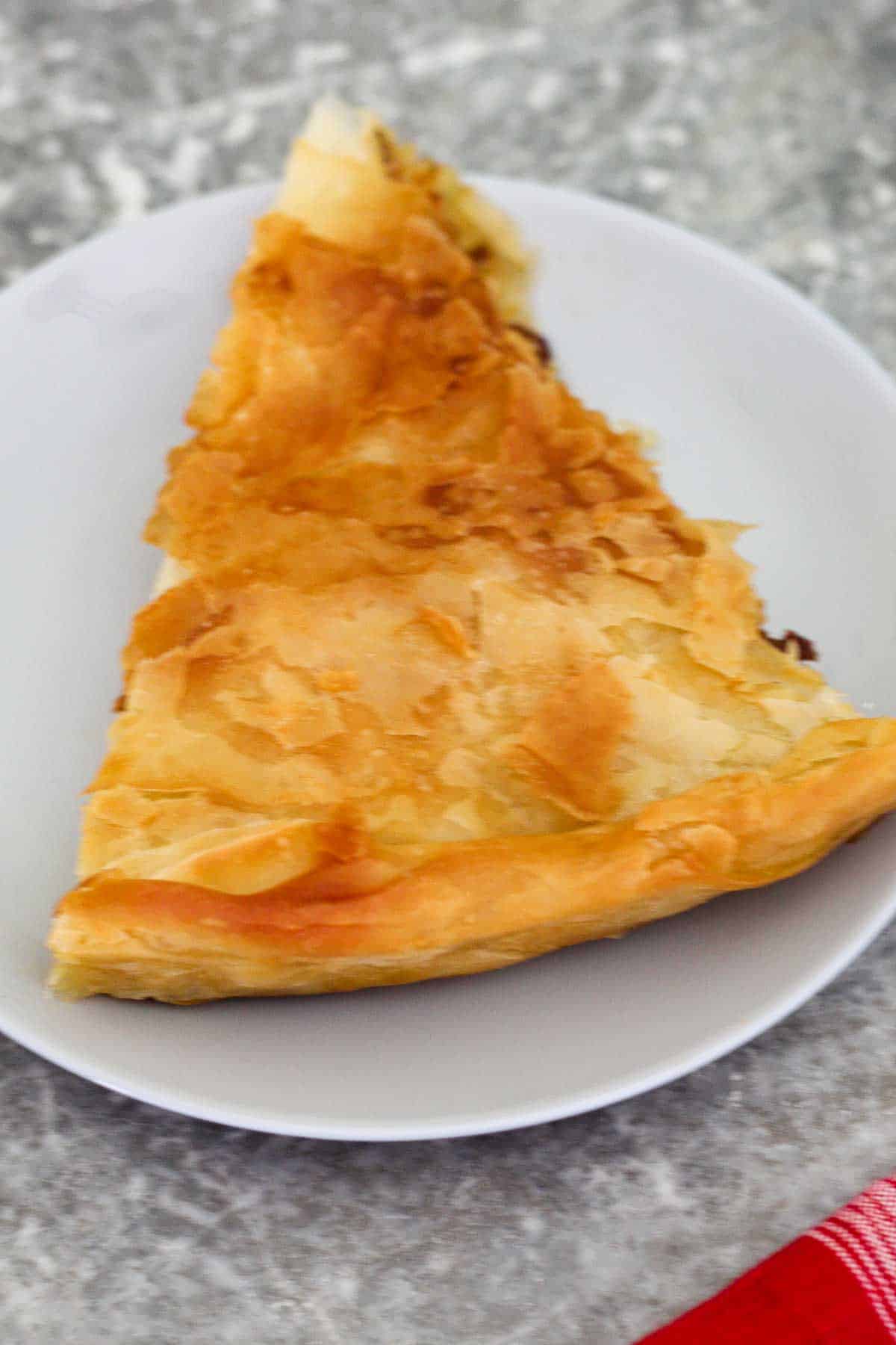 A plate showing a slice of traditional Albanian byrek (phyllo meat pie). 