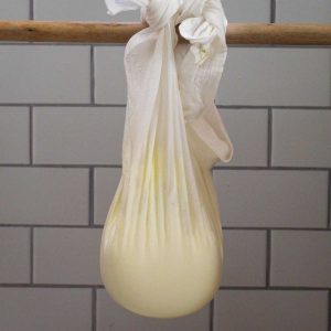 Straining yogurt on a muslin fabric hanging over a rod.