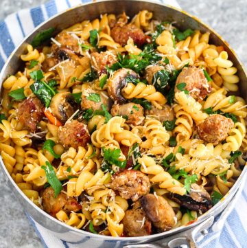 Fusilli pasta with sausages and veggies on a deep skillet, ready to serve family style.