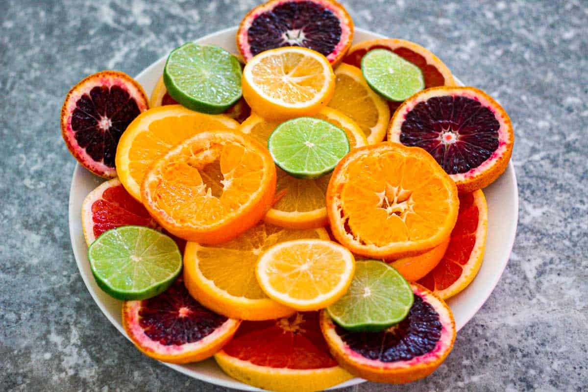 A platter of sliced citrus fruits: grapefruit, navel orange, blood orange, lime, lemons, mandarin etc