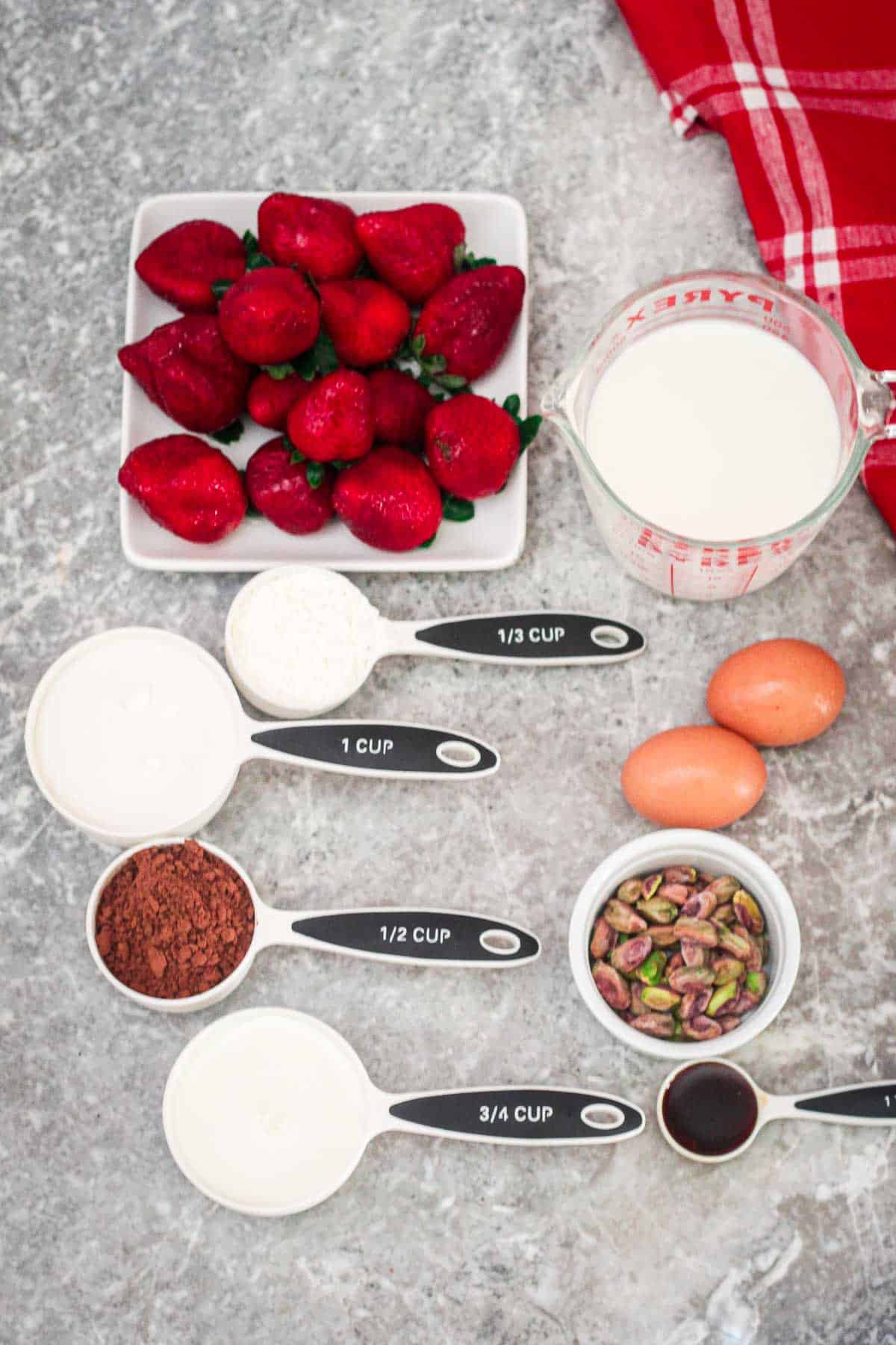 Ingredients for chocolate pudding: strawberries, milk, cornstarch, eggs, sugar, cocoa, pistachios, vanilla extract, and more milk. 