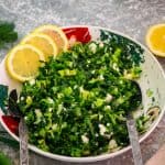A family salad platter with lettuce and dill salad, shown garnished with fresh lemon slices.