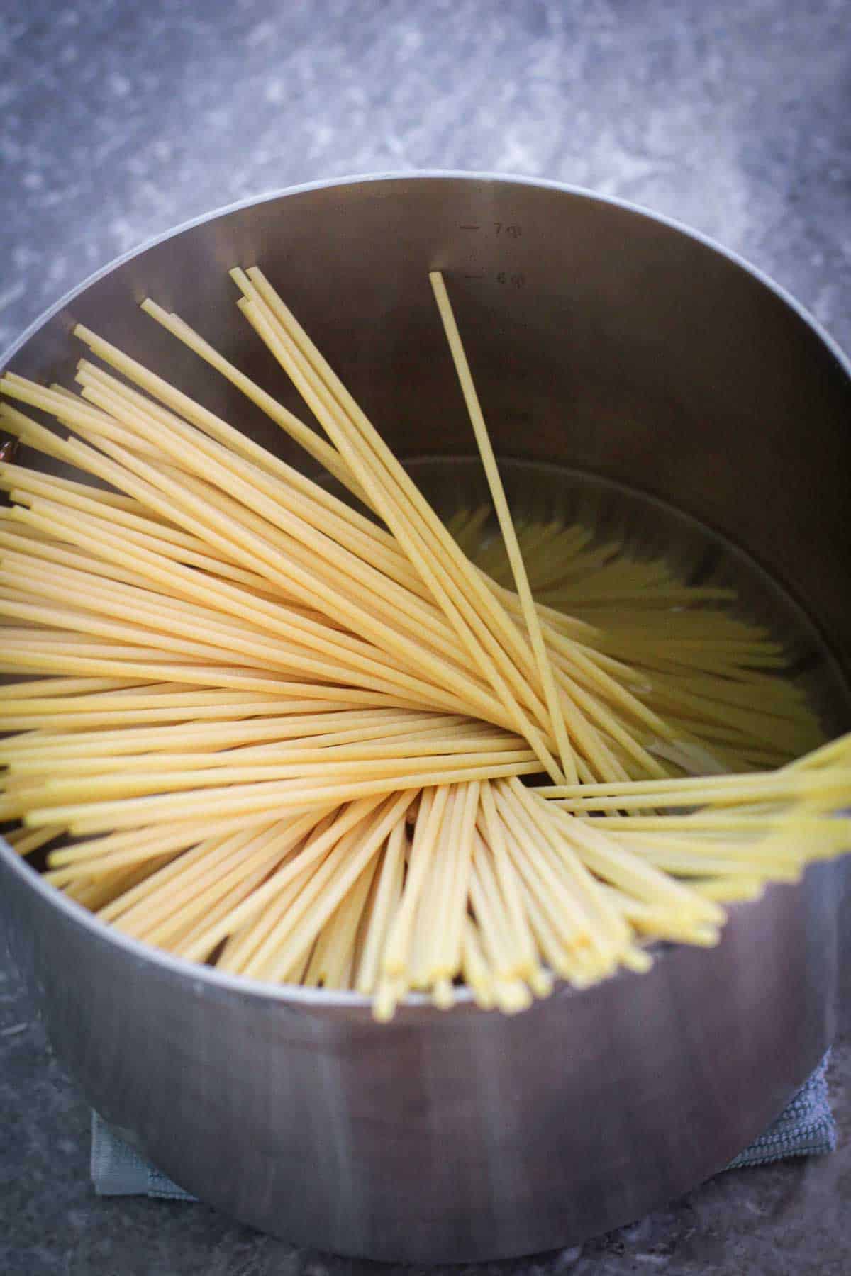 Bucatini pasta just thrown in boiling water in a big pot.