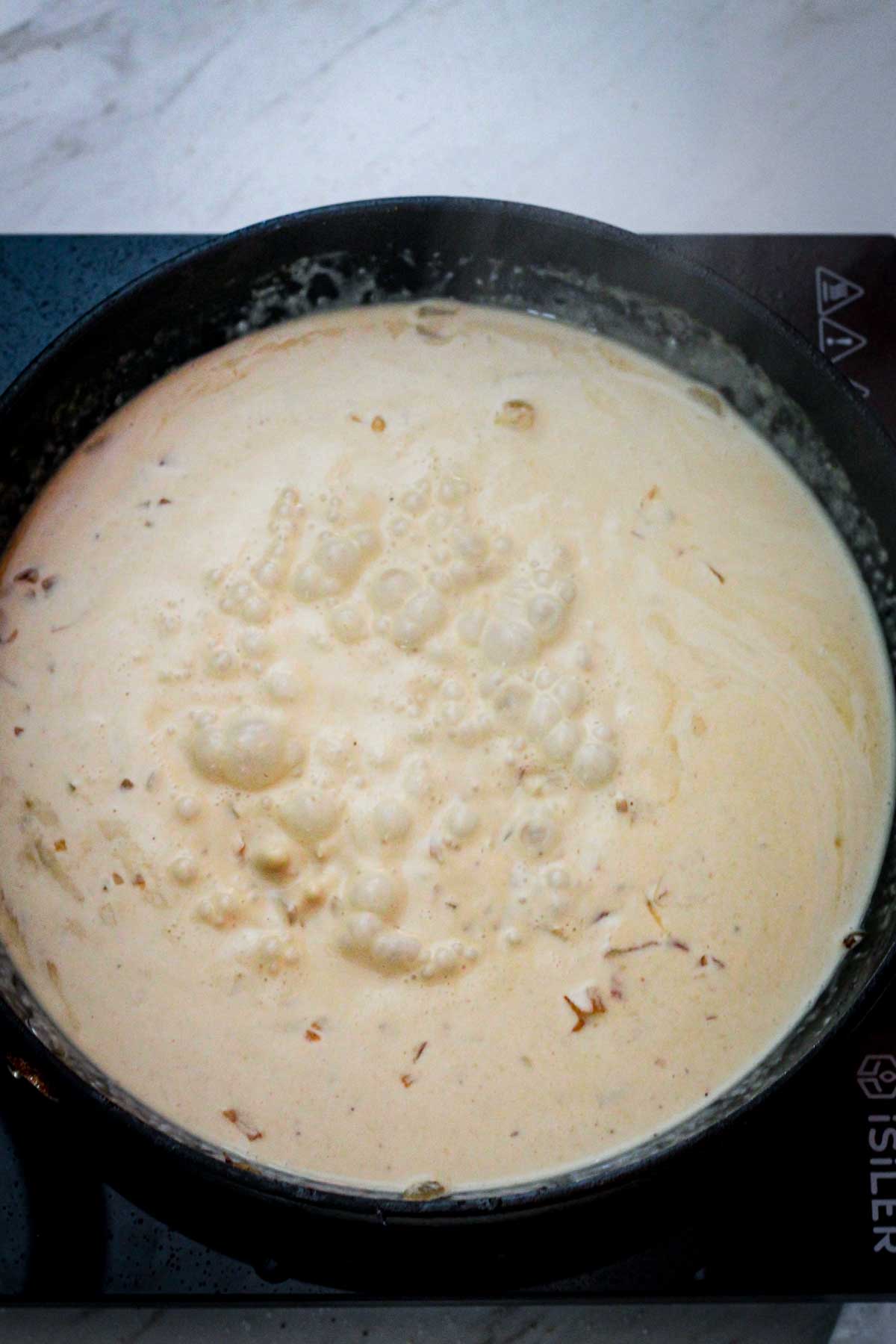 Adding cream and dijon mustard to the skillet to make the white wine sauce with dijon mustard. 