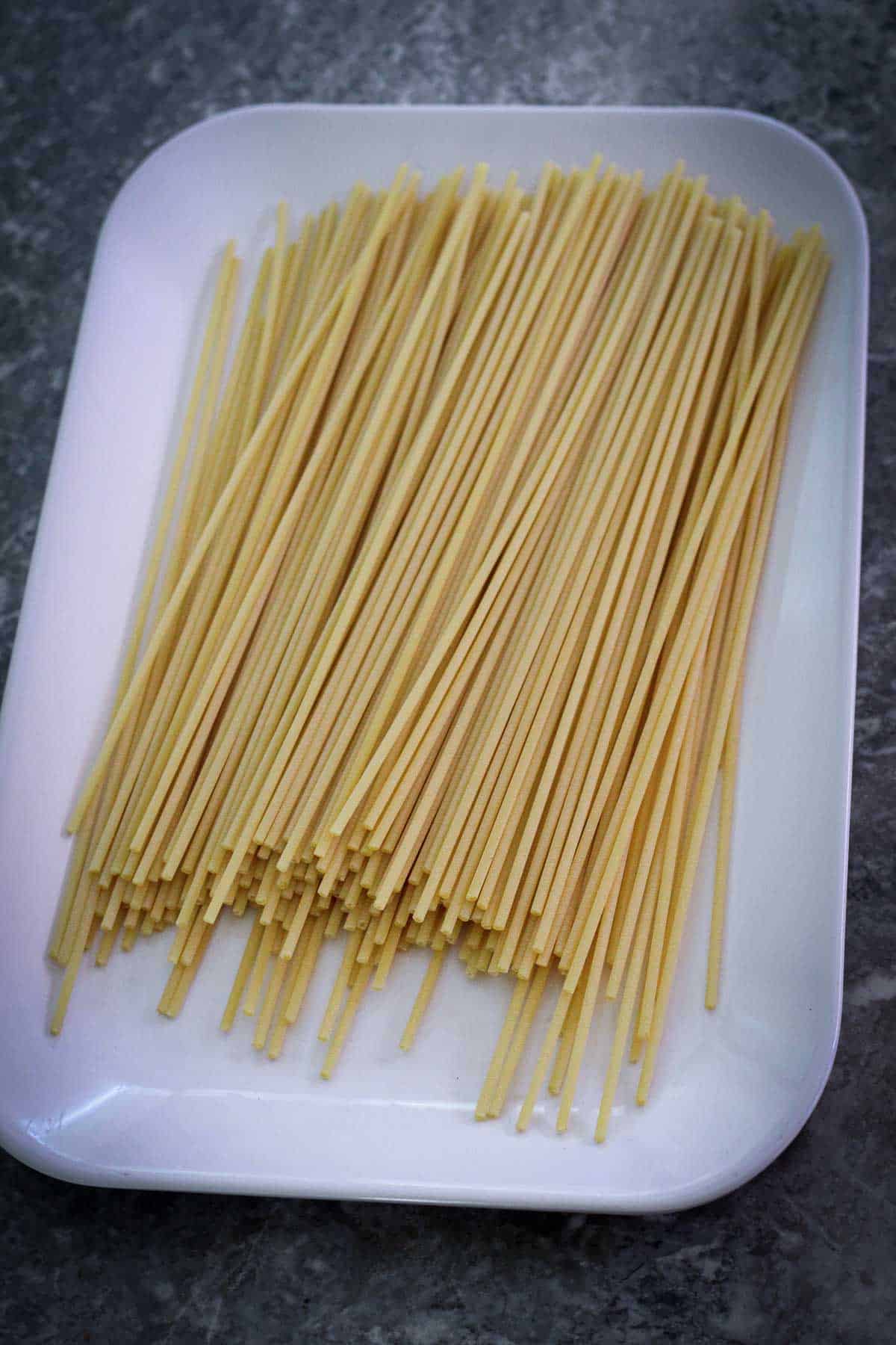 Uncooked bucatini in a rectangular platter. 