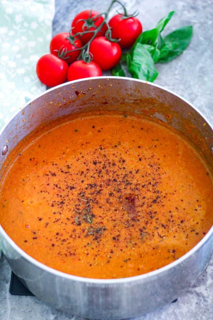 Roasted tomato soup with garlic, basil and chickpeas in a soup pot after being blended with an immersion blender. 