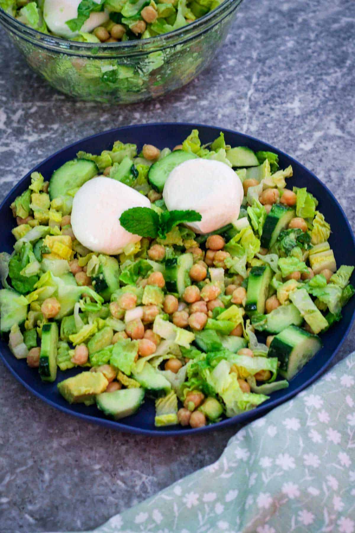 A serving of chickpea and cucumber salad with burrata, avocado, lime, mint and other ingredients. 