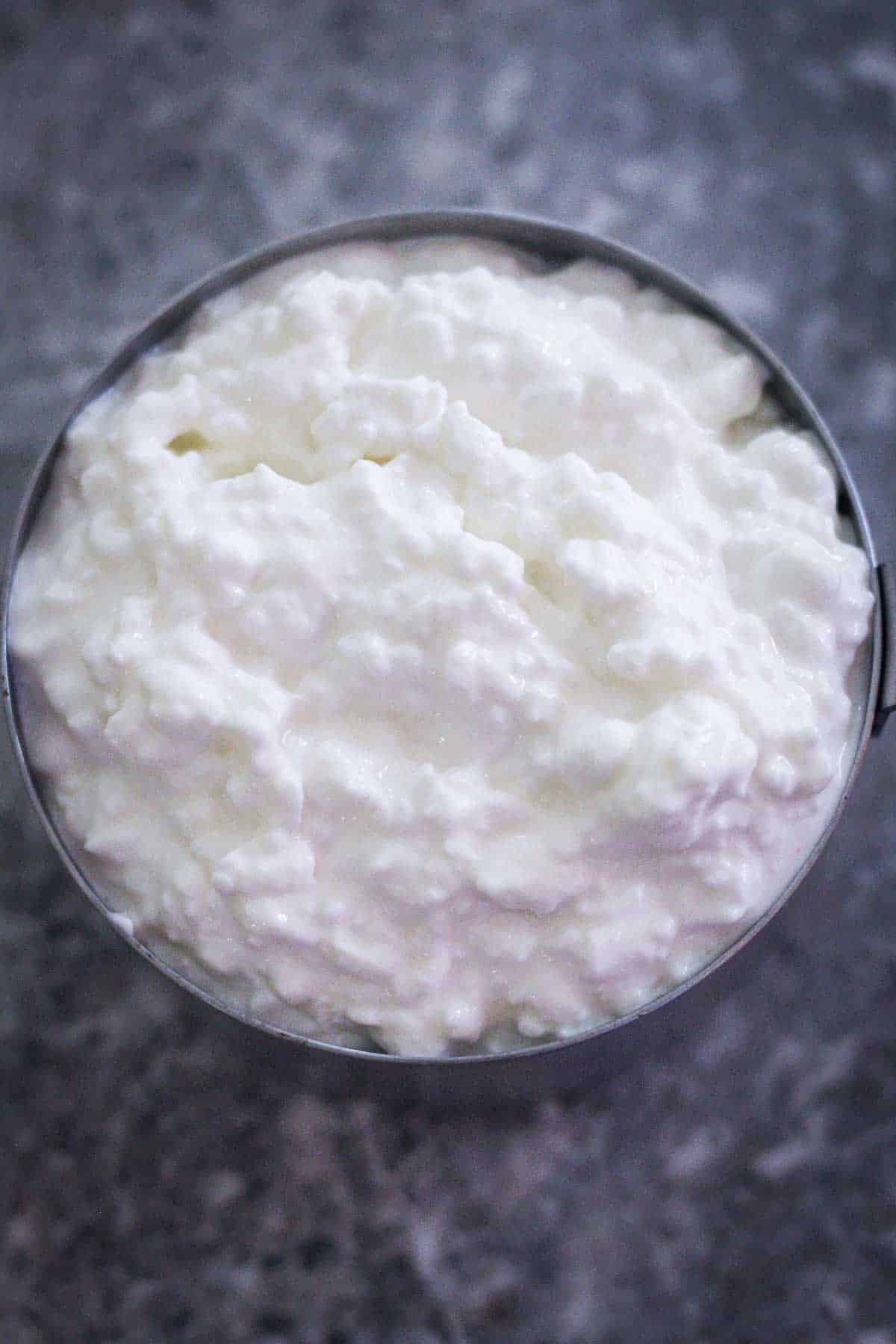 Cottage cheese on a measuring cup, close up view.