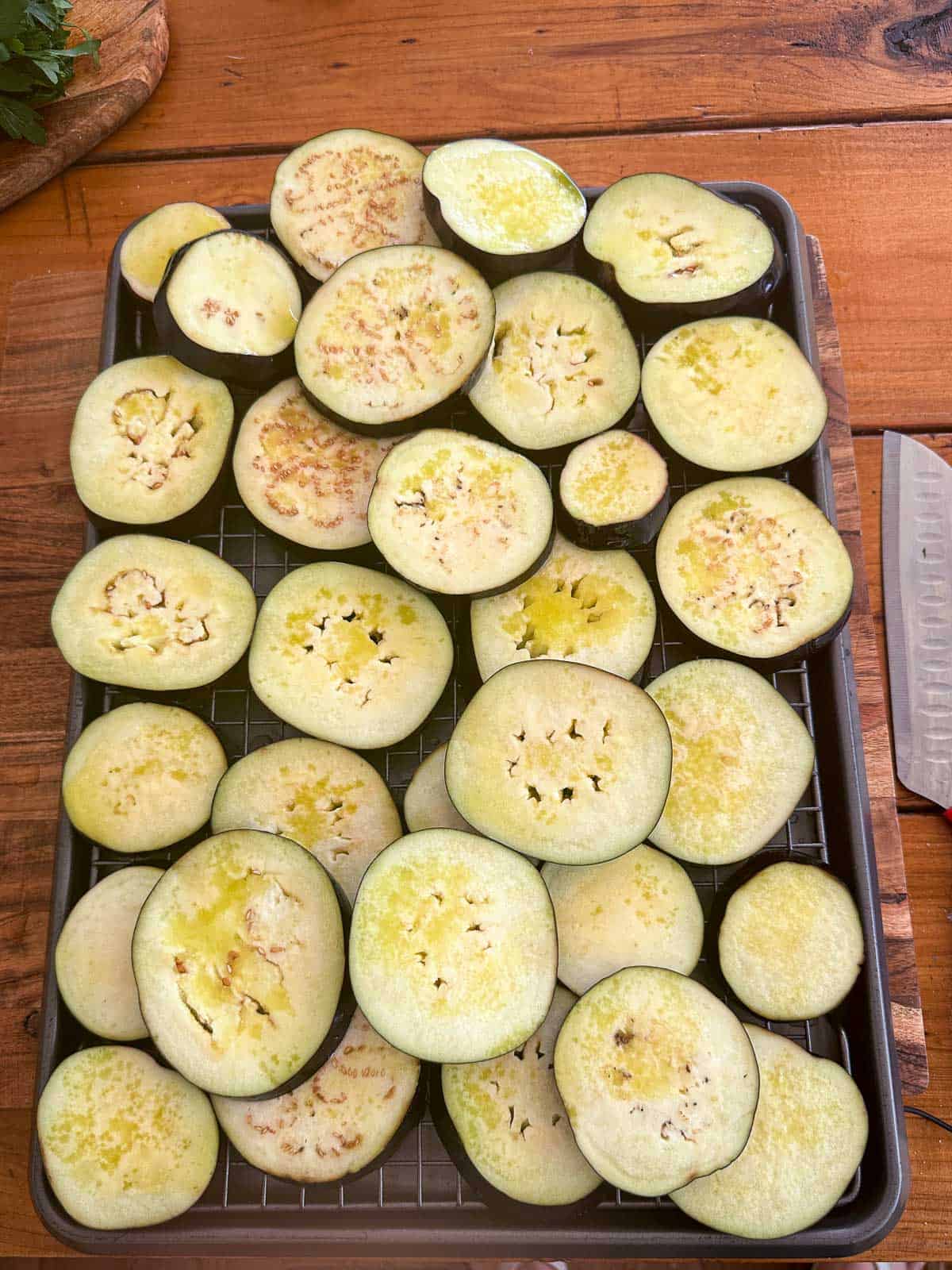 Brushed eggplant slices with olive oil on a tray, before grilling.