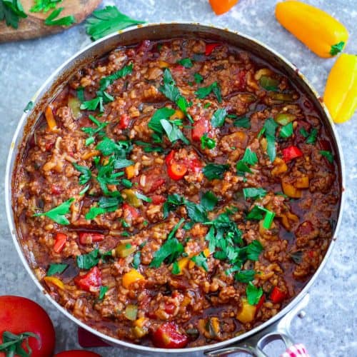 A skillet with ground beef, peppers, tomato sauce and herb garnishes!