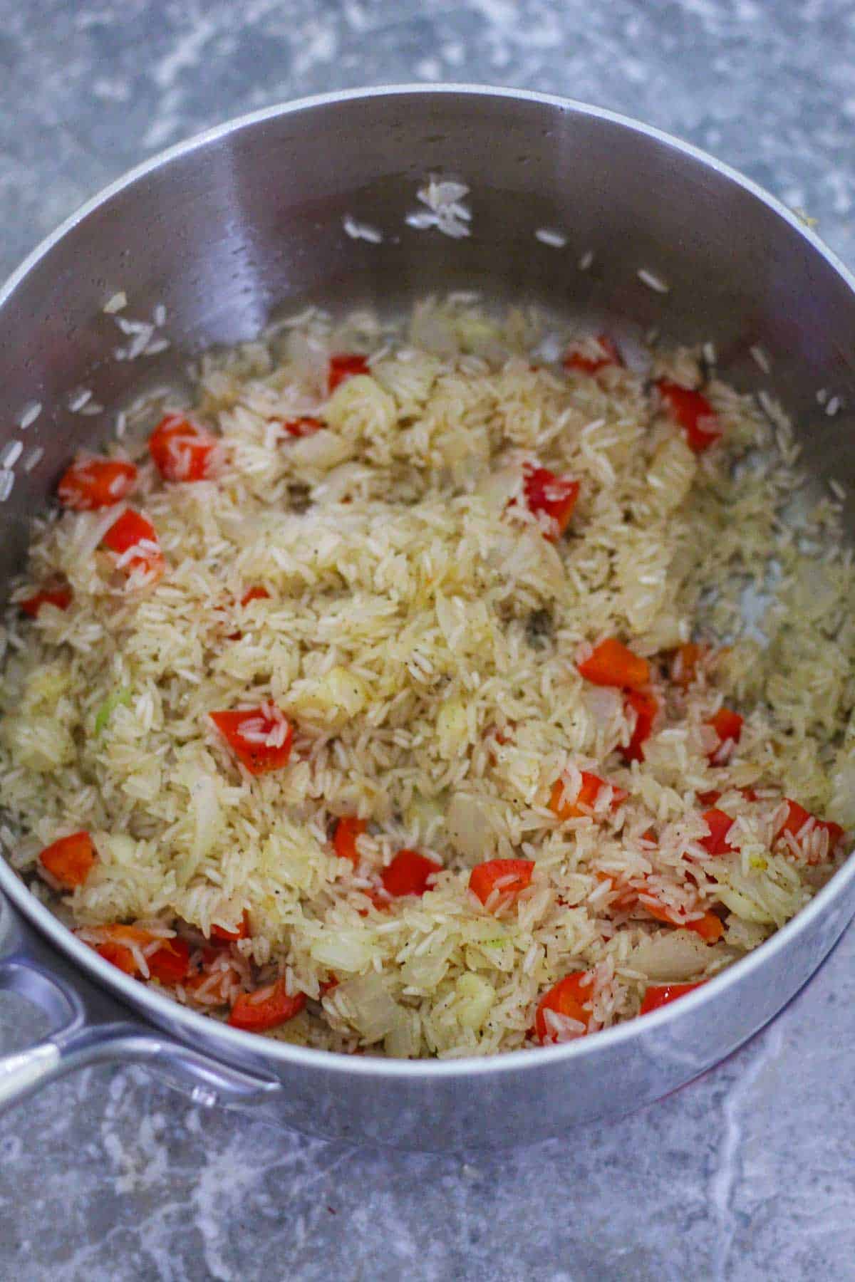 Toasting jasmine rice with the onion, garlic and red pepper. 