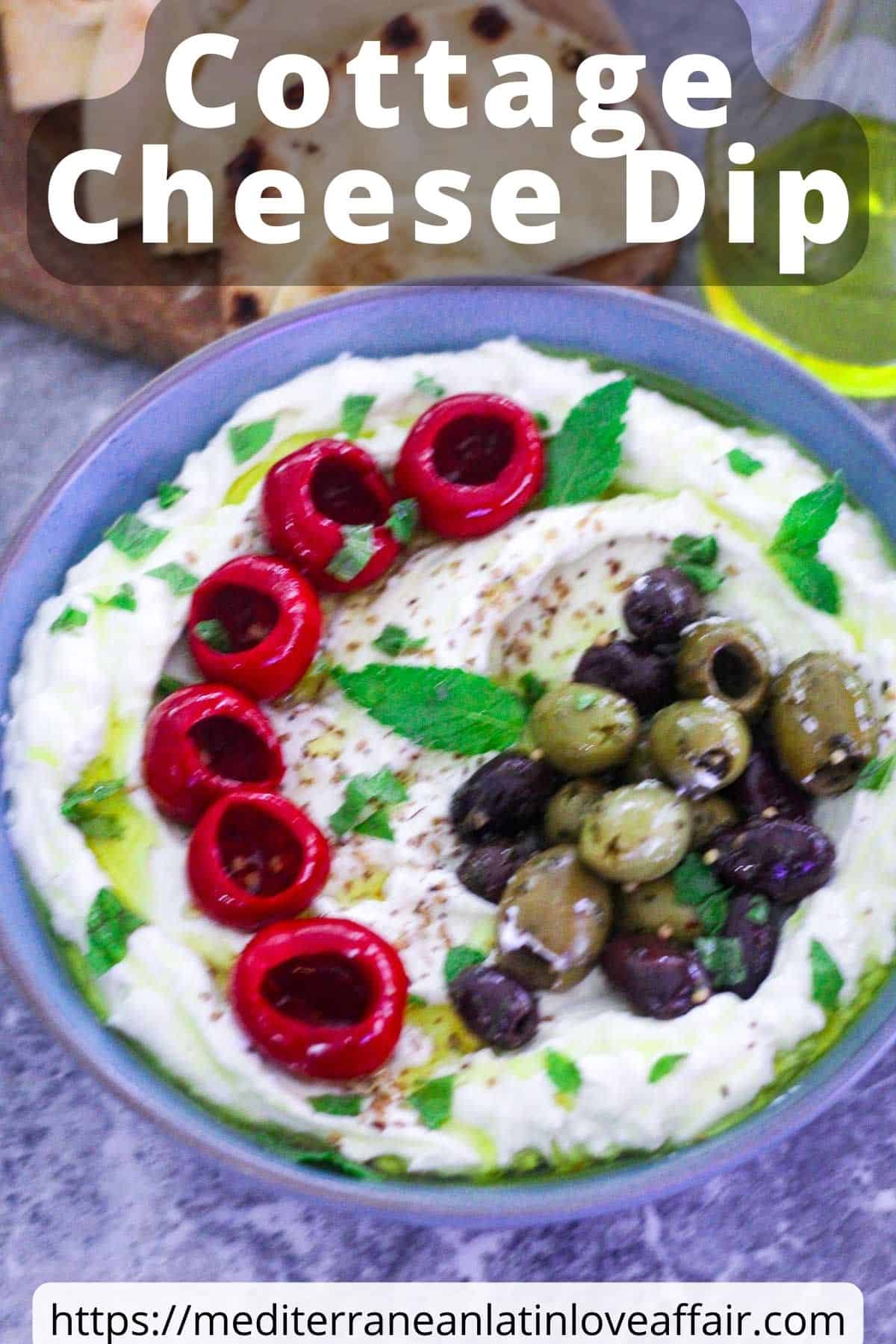 An image prepared for Pinterest. It shows a picture of the whipped cottage dip on a blue bowl, topped with olives and red peppers. There's a title bar over the picture and a website link at the bottom.