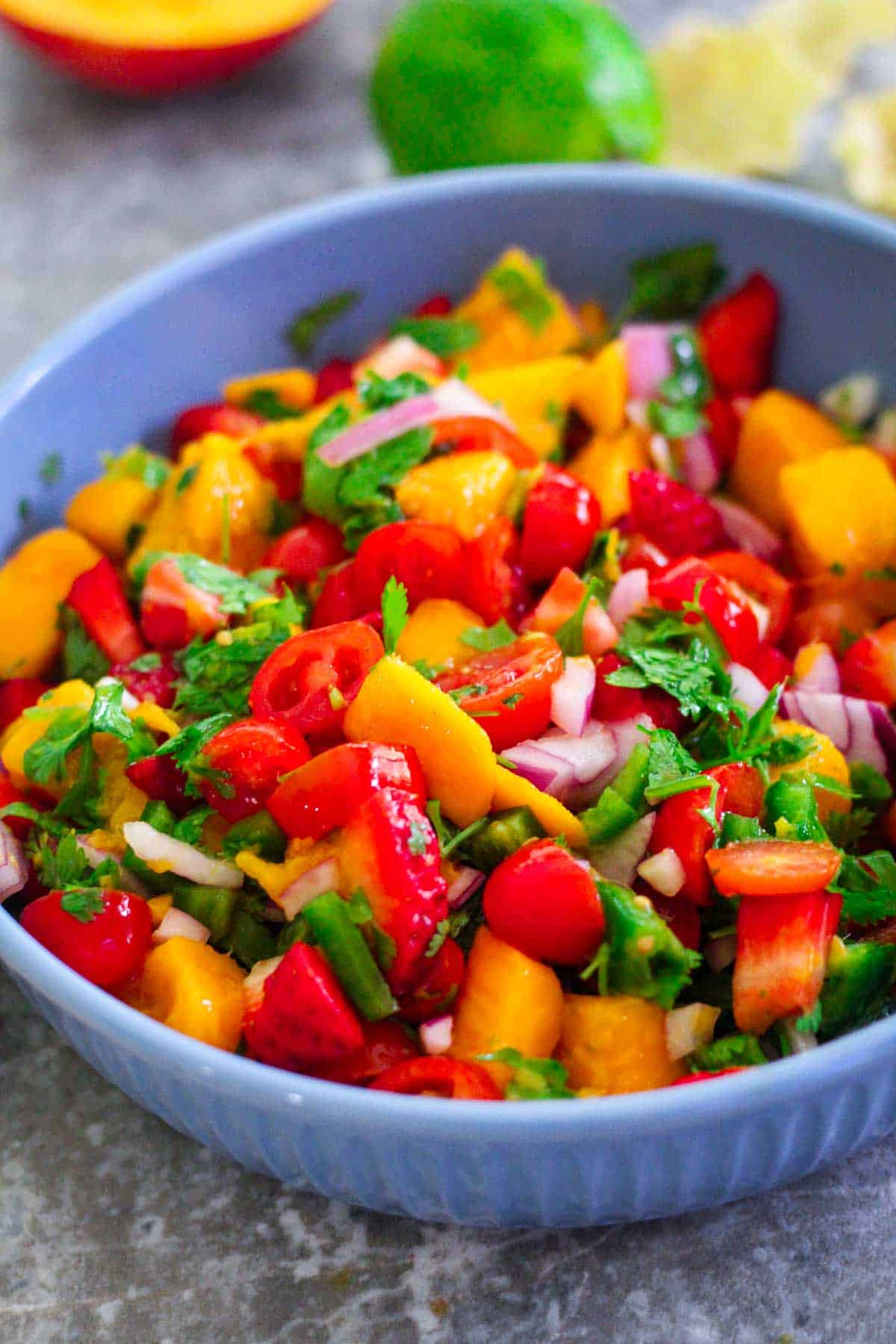 Closeup of a mango strawberry salsa, you see all the chopped ingredients mixed together. 