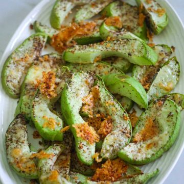 Roasted sliced chayote squash with herbs and parmesan, arranged in a platter.