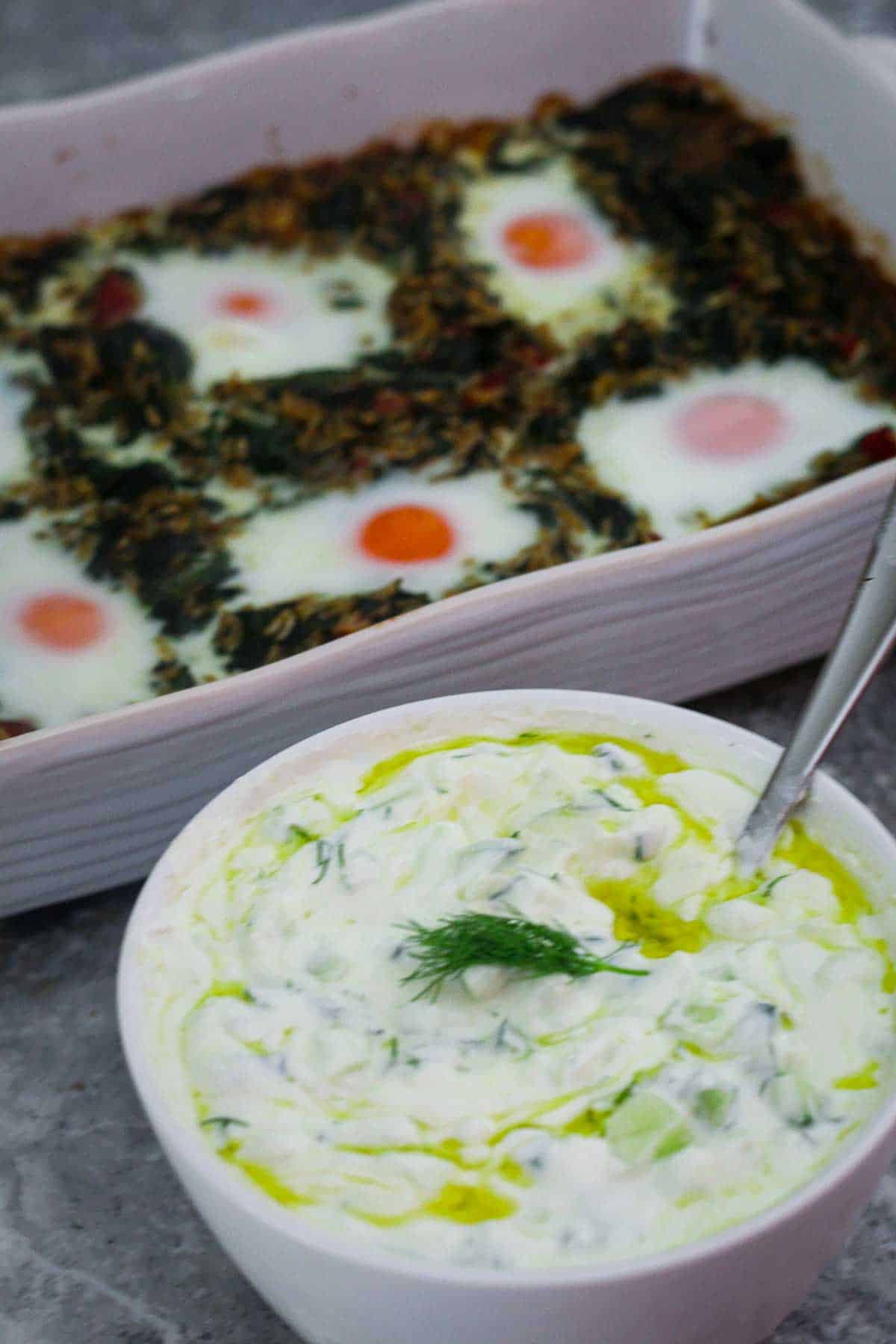 Spinach, rice and eggs bake shown next to a bowl of tarator (yogurt, cucumber and dill cold soup). 