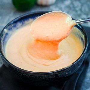 Sriracha aioli in a bowl with a serving spoon in it.