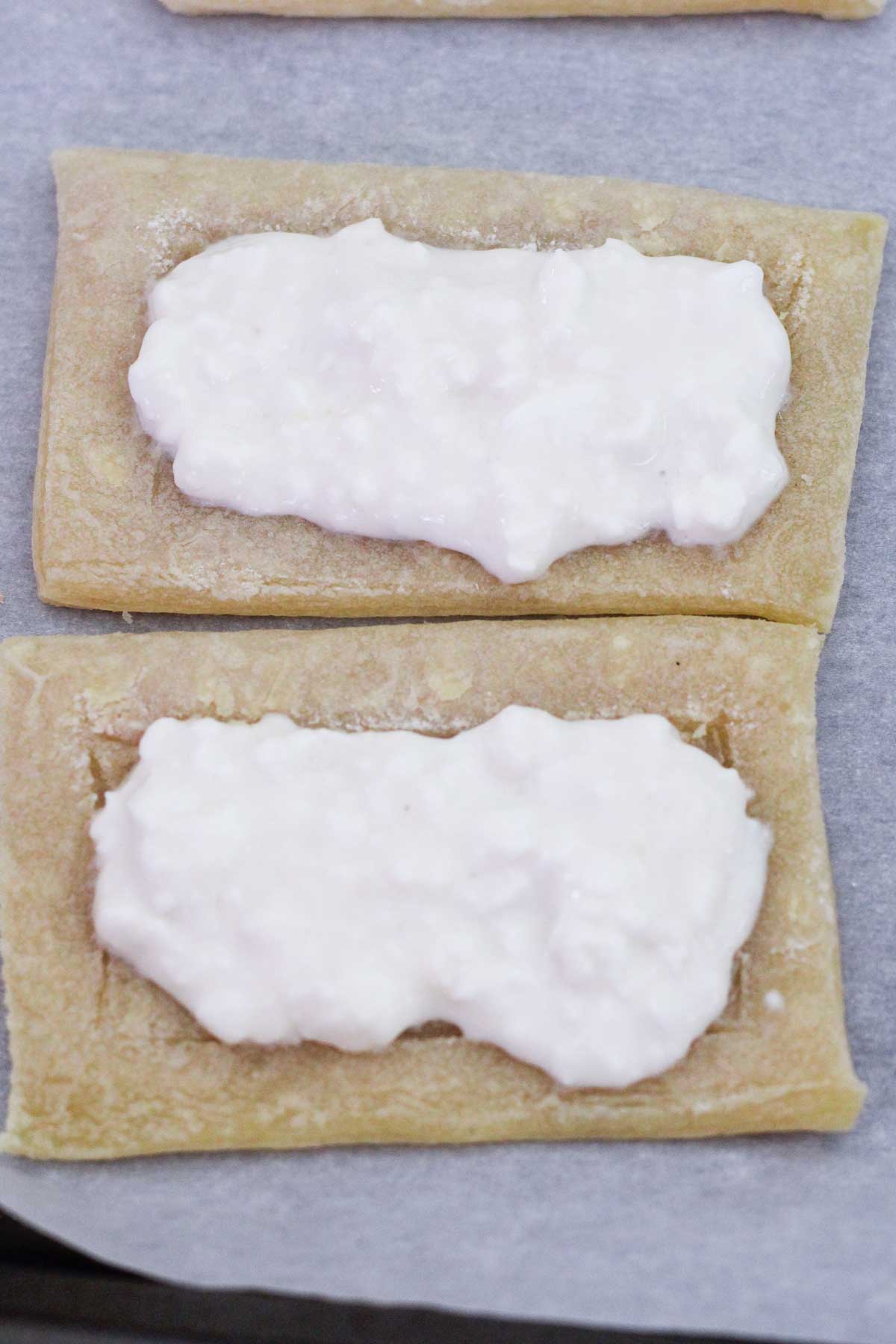 Adding whipped cottage cheese and honey over the puff pastry rectangles.