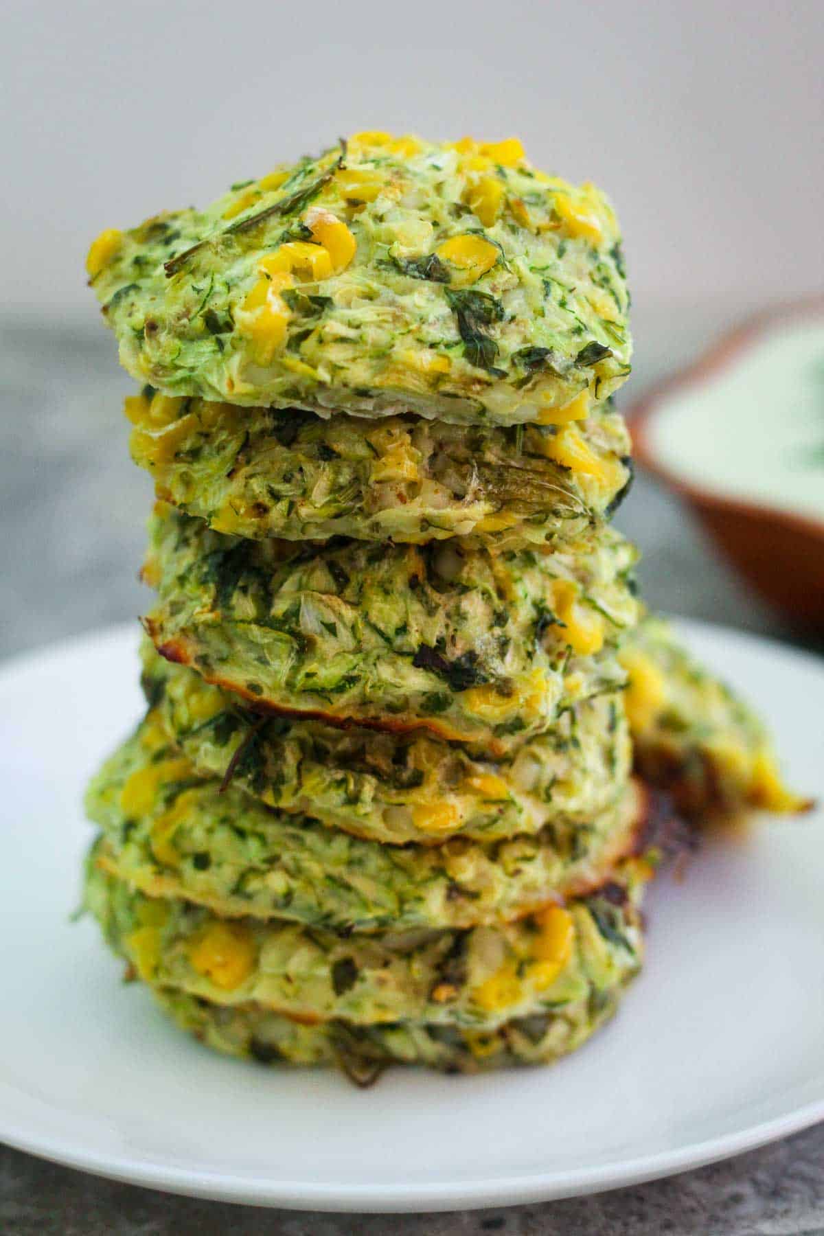 Zucchini and corn fritters, piled up in a tower shape on top of each other. 