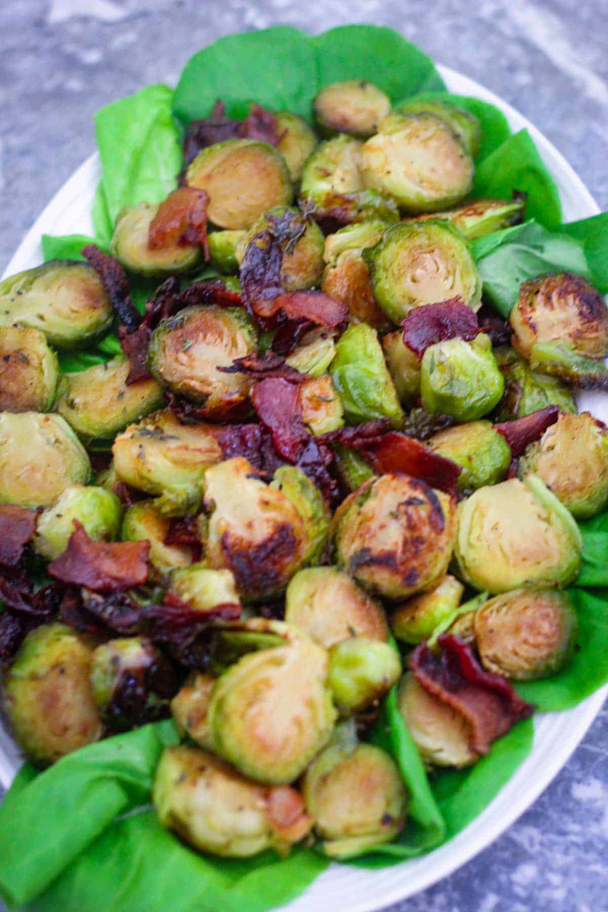 A platter showing a serving of roasted Brussel sprouts with bacon bites. 