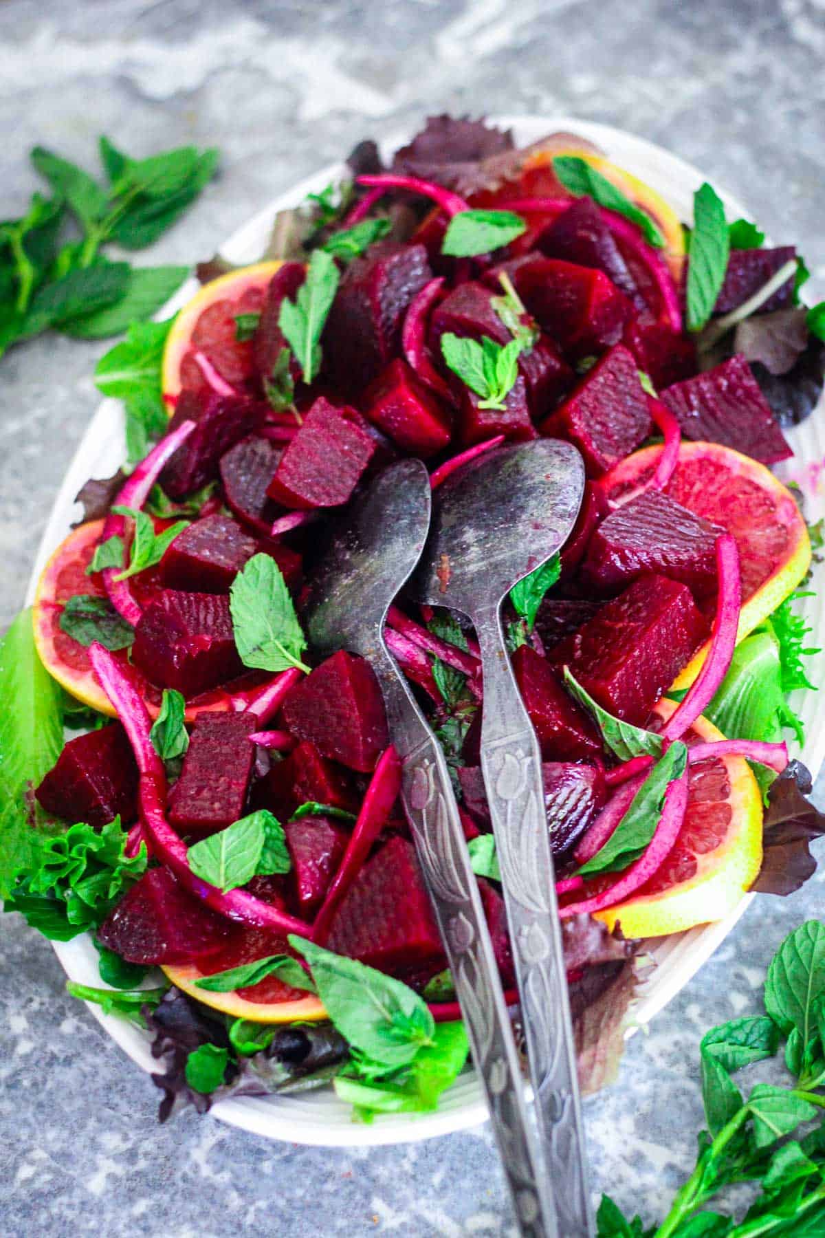 A platter with beets, mint, oranges and other ingredients making up a beautiful and vibrant salad.