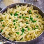 A pot with cooked gigli pasta and green peas.